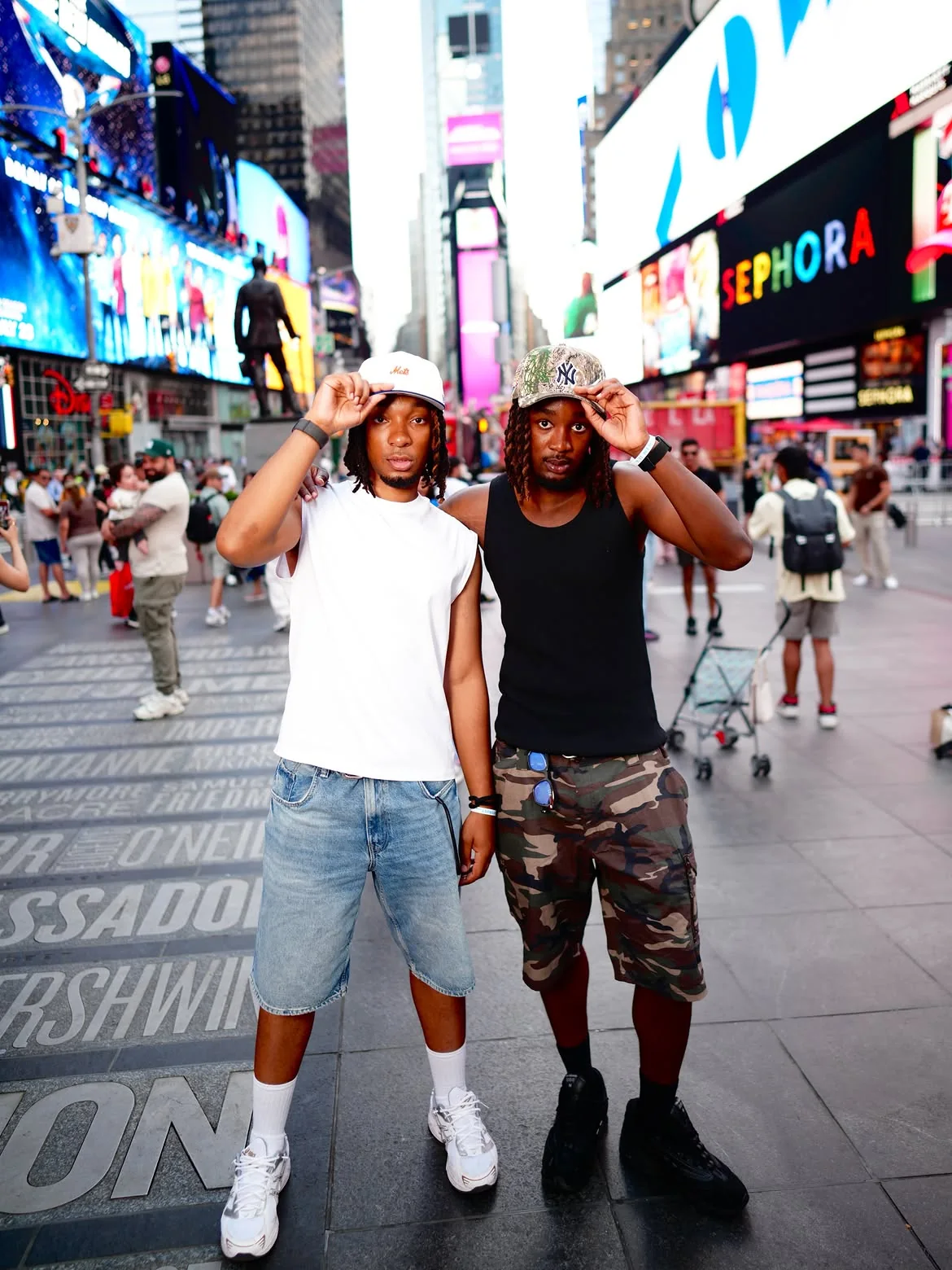 Jey et D2, casquette à la main, à Times Square, New York